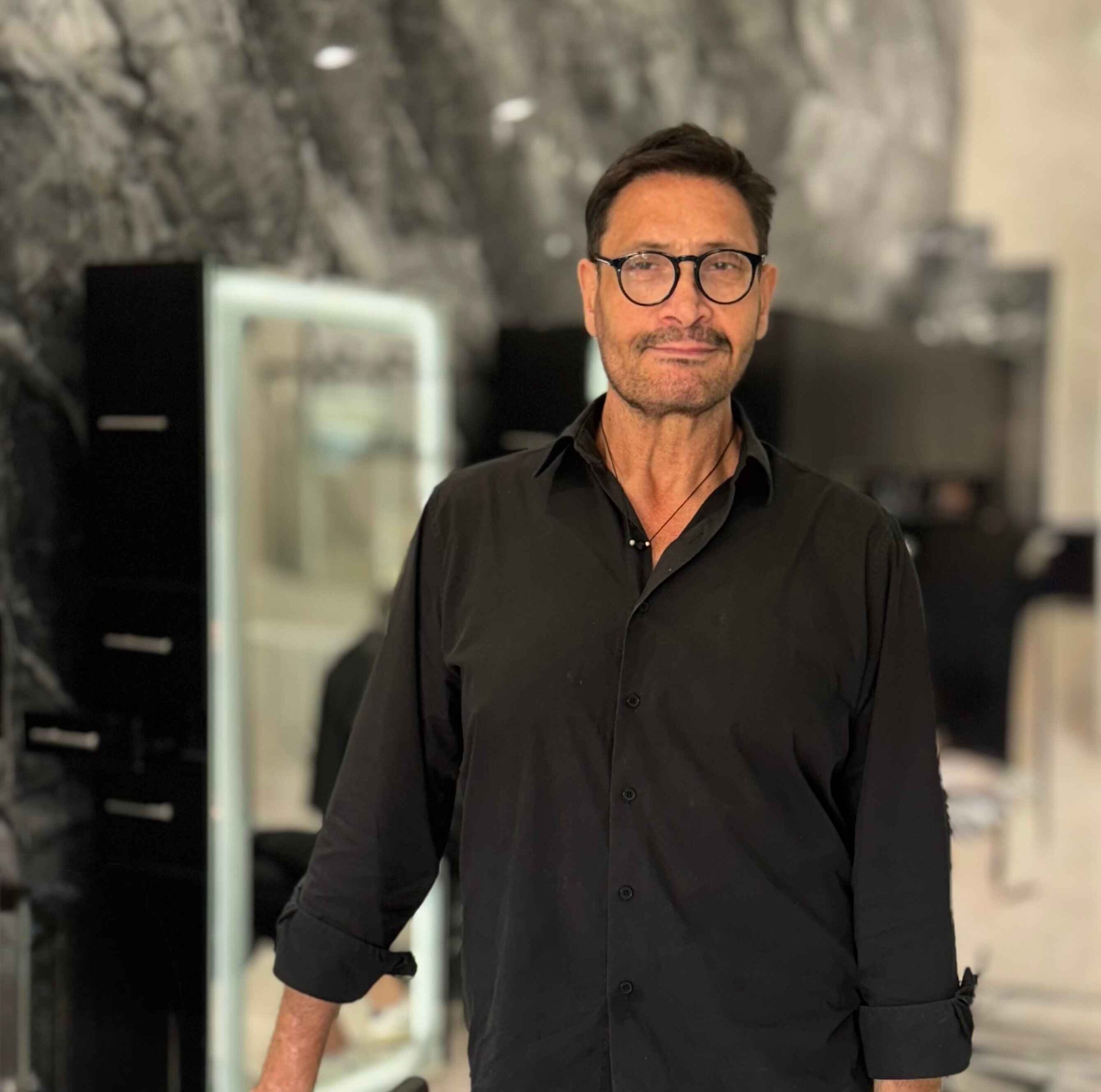 Sergios our hairstrylist wearing glasses with short hair